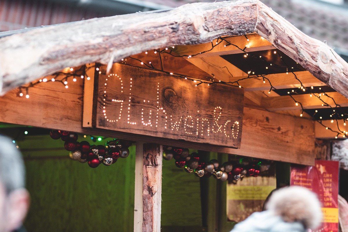 Beleuchtetes Schild „Glühwein und Co" an einer Holzhütte